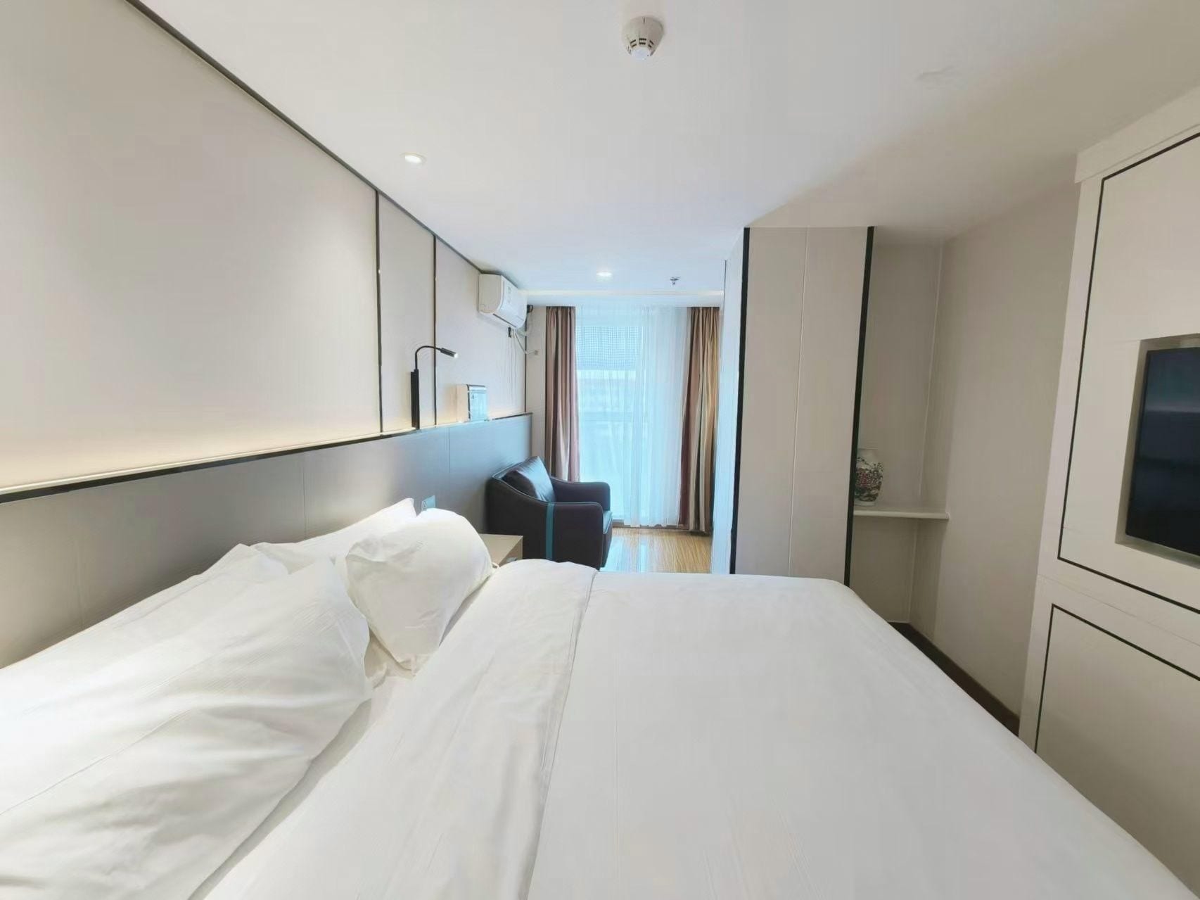 A hotel room with a large bed, a desk, a chair, and a TV.