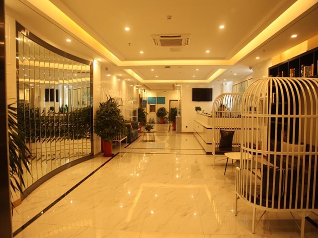 A hotel lobby with a curved reception desk, potted plants, and a seating area.