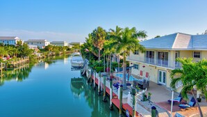 A waterfront hotel with a dock, outdoor seating, and a pool area. - Sunchasers Paradise - lux home, private pool/spa, 80' dock (Marathon)
