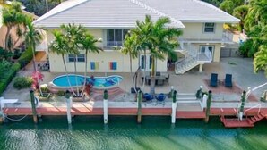 A two-story house with a swimming pool, palm trees, and a red deck. - Sunchasers Paradise - lux home, private pool/spa, 80' dock (Marathon)