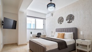Un dormitorio moderno con una cama grande, mesitas de noche, un televisor y decoración en la pared.