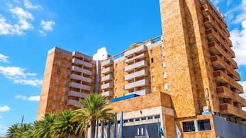 Um hotel com vários andares e design moderno, com varandas em cada pavimento e uma entrada destacada com uma placa.