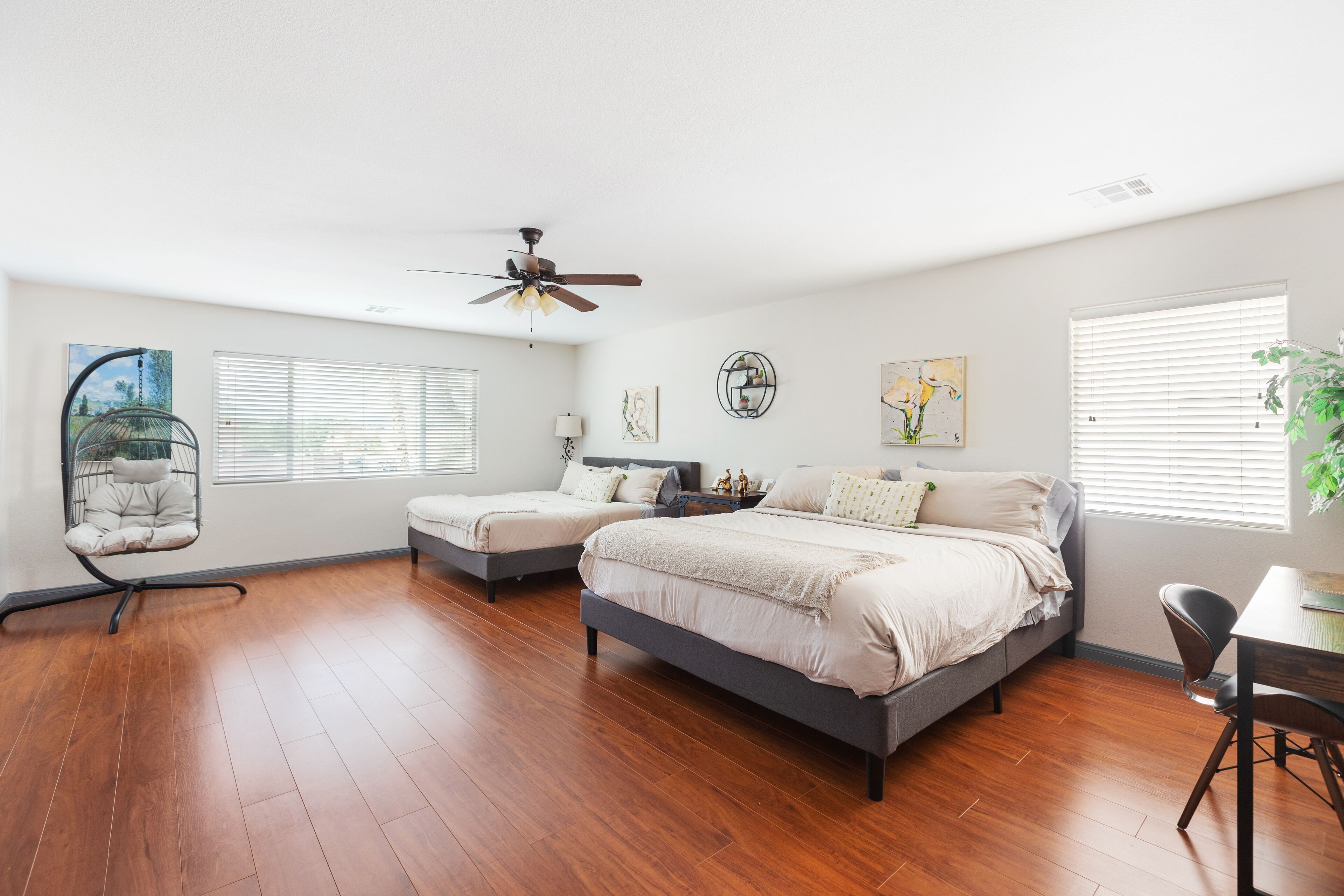 A bedroom with two beds, a ceiling fan, and a desk with a chair.