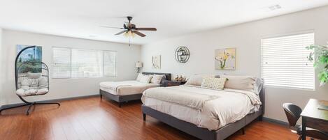 A bedroom with two beds, a ceiling fan, and a desk with a chair.