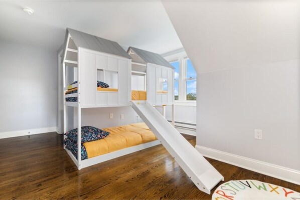Une pièce avec un lit superposé, un petit escalier et une fenêtre.