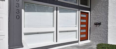 A modern building with a garage door, a wooden door, and a mailbox.