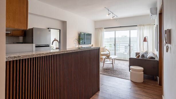 A modern kitchen with a built-in refrigerator, wooden cabinets, and a granite countertop.