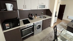 A compact kitchen with a microwave, oven, sink, and a coffee maker.