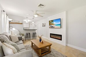 A modern living room with a sofa, a coffee table, a fireplace, and a TV mounted on the wall.