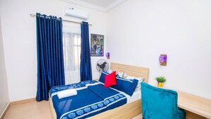 A bedroom with a bed, a fan, a small table, and a chair. - AJI (1.0)| Luxury 3BED Apartment (Ijegun, Lagos) (Lagos)