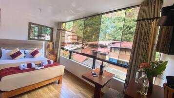 Habitación de hotel con una cama grande, un escritorio de madera, vistas a edificios a través de una ventana y un espejo en la pared.