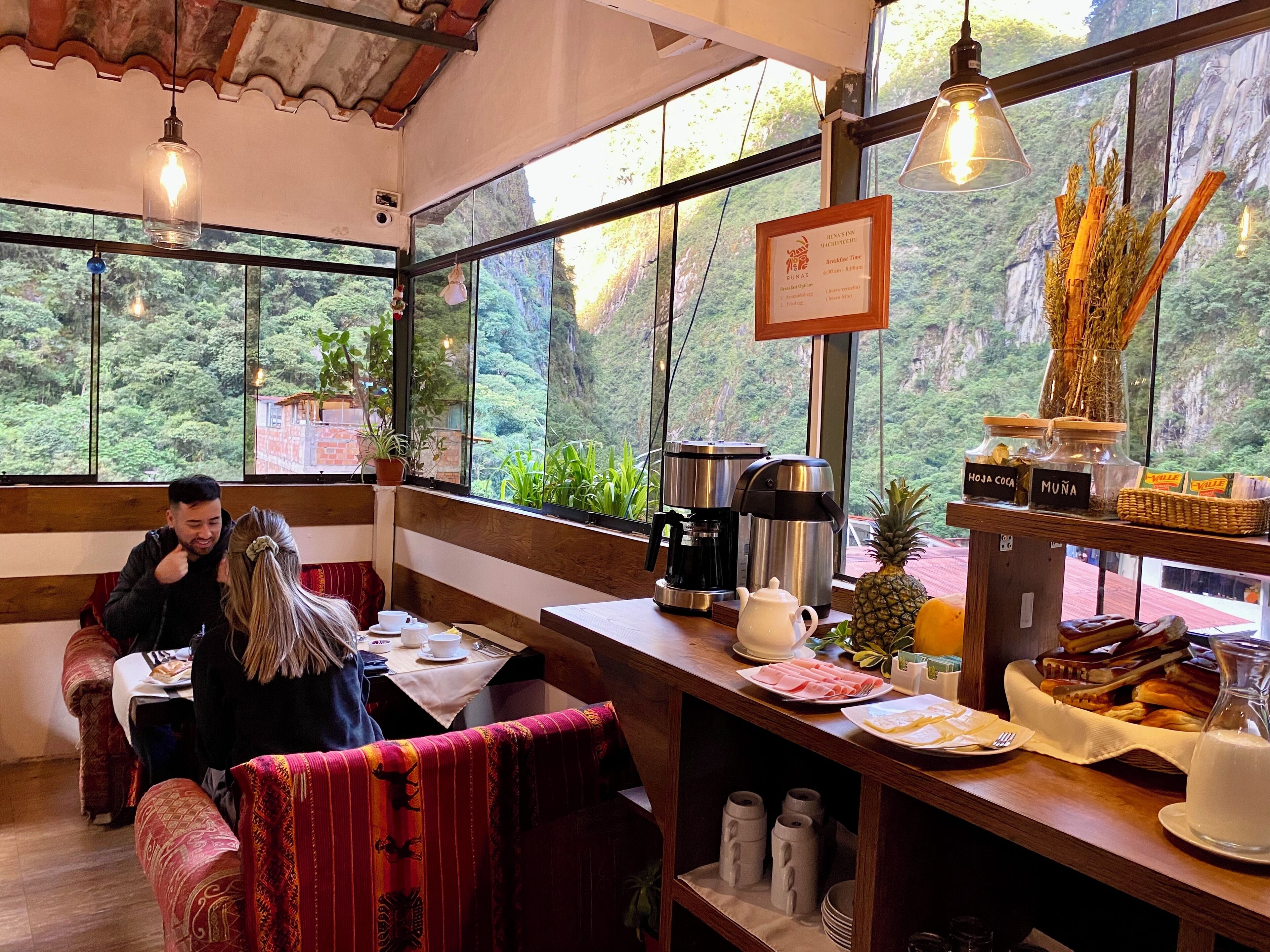 Un restaurante acogedor con muebles de madera, una estación de café y vistas a exuberante vegetación.