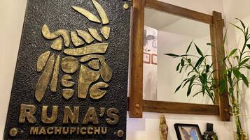 Una pared con un letrero decorativo que dice "RUNA'S MACHUPICCHU" y un espejo encima.