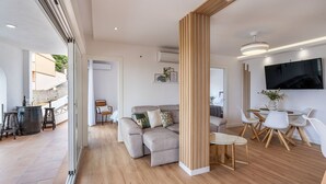 A modern living room with a sofa, a dining table with chairs, and a TV mounted on the wall. - Villa Mediluzma Almuñécar by Ruralidays (Granada)