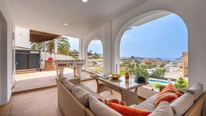 A spacious balcony with a foosball table, wicker furniture, and a view of a pool and buildings. - Villa Mediluzma Almuñécar by Ruralidays (Granada)