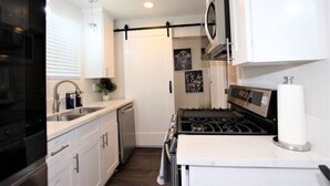 Uma cozinha compacta com armários brancos, um fogão preto e um micro-ondas.