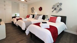 Quarto de hotel com duas camas, ventilador de teto e decoração de parede.