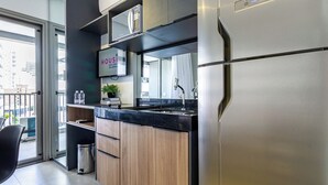 A modern kitchen with a stainless steel refrigerator, wooden cabinets, a black countertop, and a sign that reads "HOSI". - 360 VN Vergueiro (São Paulo)