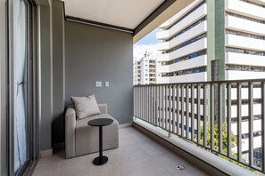 Relax on the balcony with a sofa and table, taking in the view of the surrounding area and nearby building.