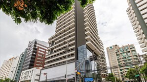 A modern high-rise building with multiple floors, large windows, and a prominent central tower. - 360 VN Vergueiro (São Paulo)