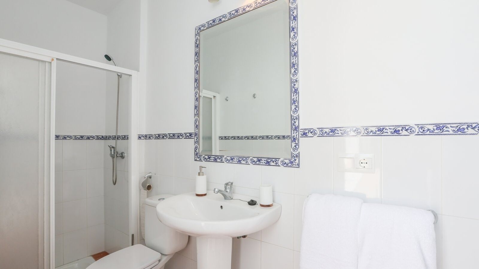 Ein Badezimmer mit Dusche, Waschbecken und einem Spiegel mit dekorativem Rahmen.
