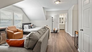 Un dormitorio estilo loft moderno con techo inclinado, una cama, un sofá y una pequeña zona de estar.