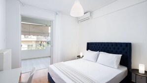 Ein Schlafzimmer mit einem großen Bett, einem Nachttisch mit Lampe und Blick auf den Balkon.