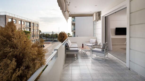 Ein moderner Balkon mit einer Couch, Stühlen und einem Tisch.