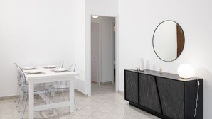 Ein moderner Essbereich mit einem weißen Tisch und Stühlen, einer schwarzen Marmorkonsole mit Spiegel und einem Flur, der in einen weiteren Raum führt.