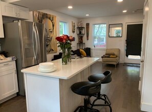 A modern kitchen with a central island, bar stools, and a refrigerator. - Cozy 2/1.5 Getaway in Lily Ponds (Washington)