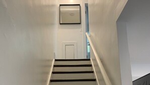 Eine Treppe mit weißen Wänden und einer Handläufe, die zu einer Tür oben führt.