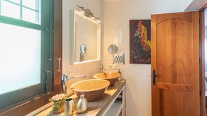 A bathroom with two large, round, textured sinks, a mirror, and a wooden door. - Casa Bea Torrox by Ruralidays (Málaga)