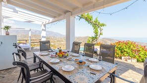 A dining table set for six with chairs, a view of the mountains, and a pergola overhead. - Casa Bea Torrox by Ruralidays (Málaga)