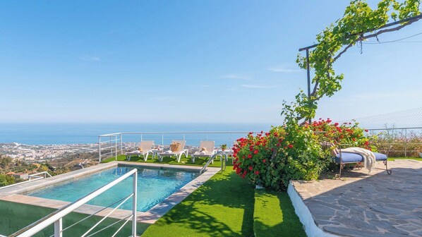 A pool with a view of the sea, a garden with red flowers, and a lounge area with chairs. - Casa Bea Torrox by Ruralidays (Málaga)