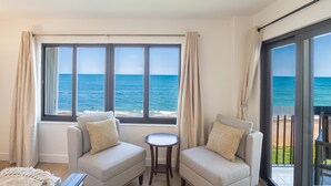 A room with two sofas facing a large window overlooking the sea.