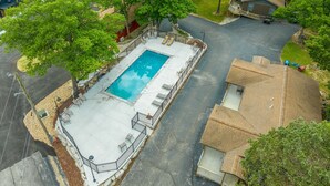 An aerial view of a residential area with a swimming pool surrounded by a fence, trees, and a small building. - 2BR Duplex Cabin w/Community Pool + Boat dock (Branson West)