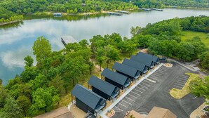 A lakeside hotel with multiple buildings, a parking lot, and boats on the lake. - 2BR Duplex Cabin w/Community Pool + Boat dock (Branson West)