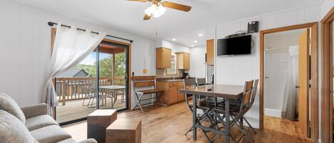 A modern kitchen with wooden cabinets, a dining area with a table and chairs, and a ceiling fan.