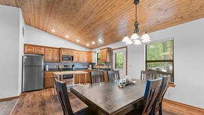 Une cuisine moderne avec des meubles en bois, des appareils électroménagers en acier inoxydable et une grande table à manger.