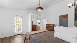 Ein Schlafzimmer mit einem Bett, einer Holzkommode und einer Tür mit einem Fenster.