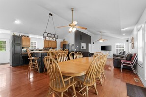 A spacious kitchen with wooden cabinets, a central island with chairs, and a dining table.