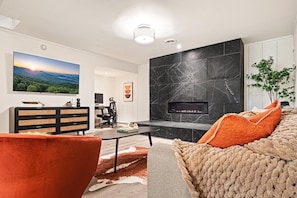 A modern living room with a fireplace, a television, and a sofa.