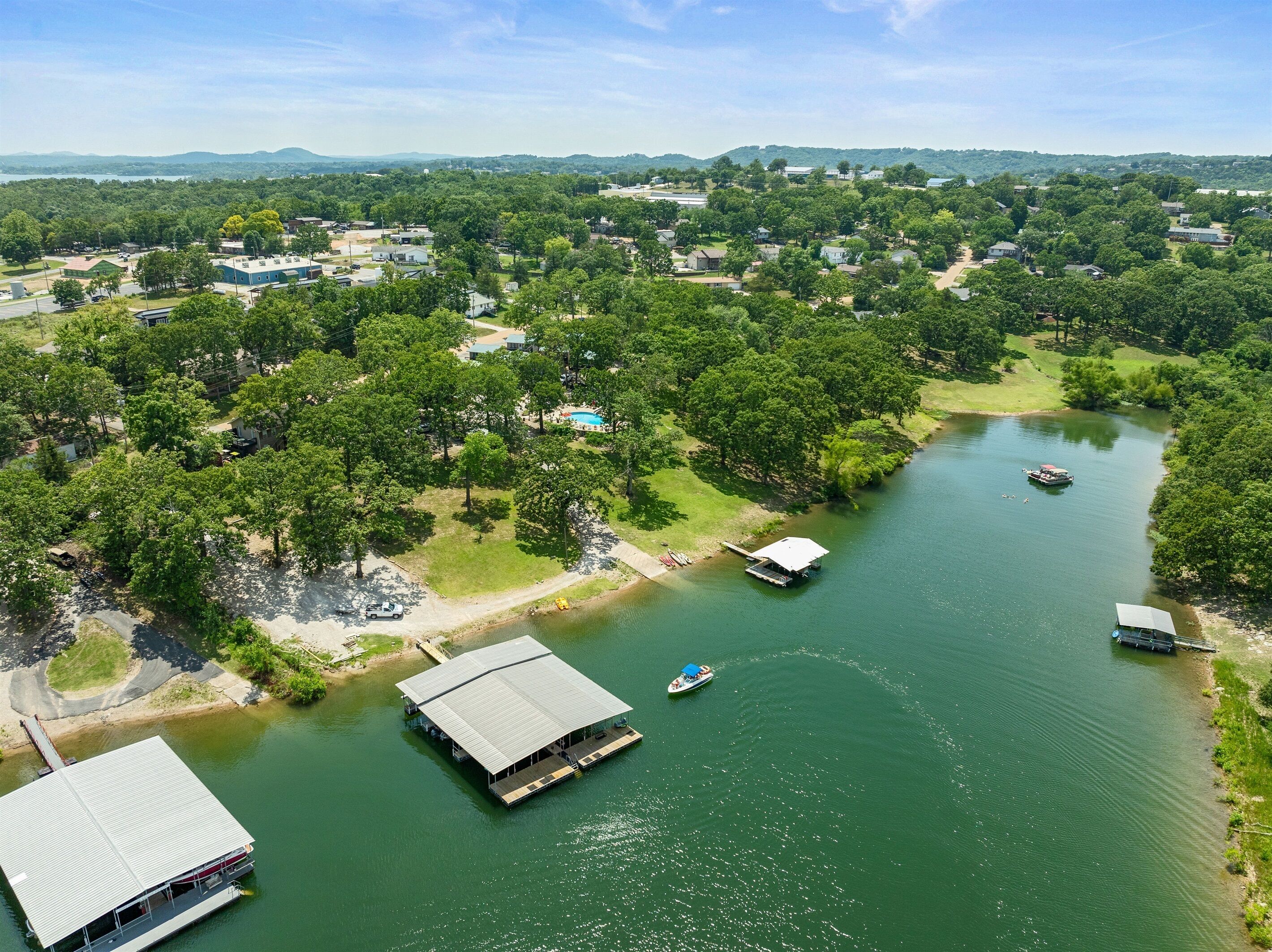 An aerial view of a lakeside area with a dock, a floating structure, and surrounding residential buildings.