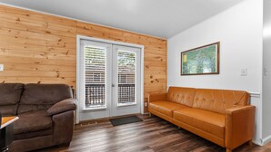 Um quarto com um sofá de couro marrom, outro de couro laranja e uma parede de madeira.
