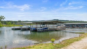 A boat dock with a covered area and a small boat in the foreground. - Lakefront Studio Cabin w/ Pool + Swim & Boat dock (Kimberling City)