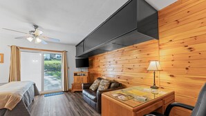 A room with a bed, a sofa, a desk, and a ceiling fan. - Lakefront Studio Cabin w/ Pool + Swim & Boat dock (Kimberling City)