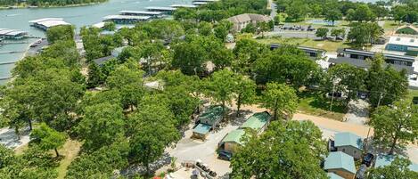 Vista aérea de um resort com piscina rodeada por árvores, um píer e vista para um lago e colinas.