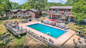 Un espace piscine avec des chaises longues, un barbecue et une terrasse dotée d’une rambarde.