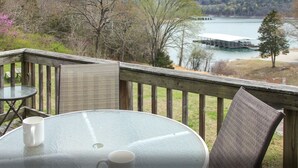 Une terrasse avec une table ronde et des chaises, donnant sur un lac et un quai.