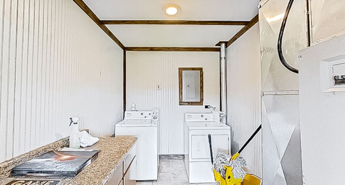 A laundry room with two washing machines, a dryer, and a small sink with a towel.